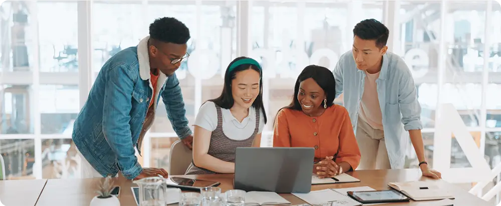 4 diverse workers smile whilst looking at laptop screen